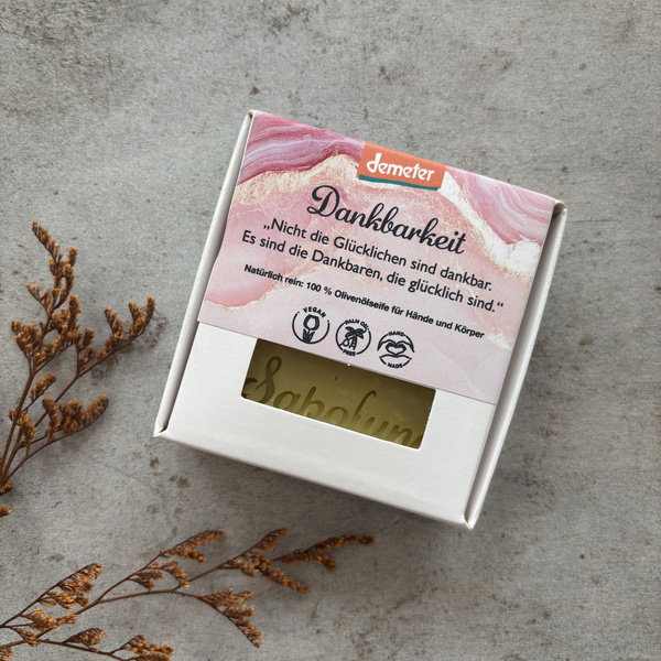 KI generiert: Eine Seife in einer Verpackung mit dem Text: „Nicht die Glücklichen sind dankbar. Es sind die Dankbaren, die glücklich sind.“