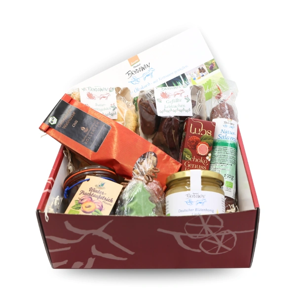KI generiert: Geschenkkorb mit verschiedenen Feinkostprodukten. Enthält u.a. Brotaufstrich, Honig und Schokolade.