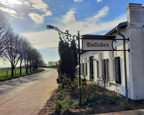 KI generiert: Straße am Land mit einem Gebäude, Schild mit "Hofladen".
