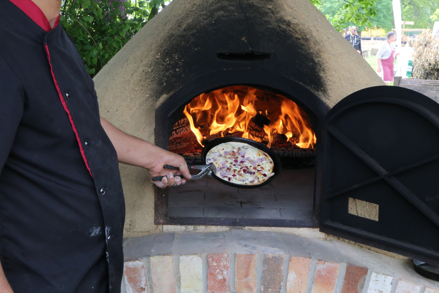 KI generiert: Person backt Flammkuchen im Holzofen.