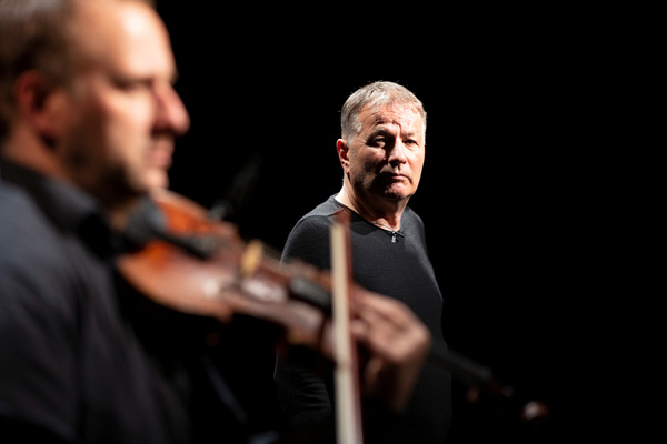 KI generiert: Zwei Personen auf einer Bühne; eine spielt Geige, eine sieht nachdenklich in die Kamera.