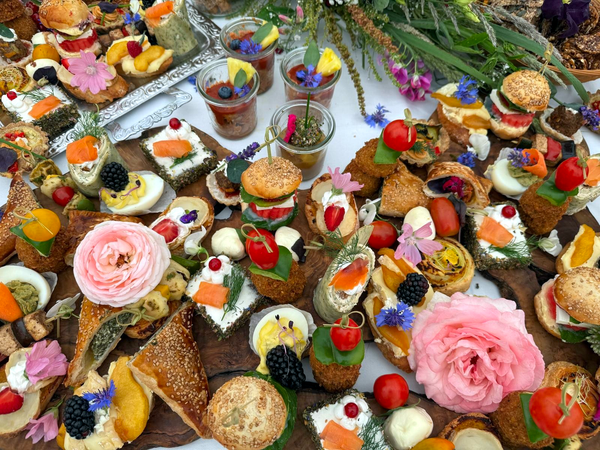 KI generiert: Eine Vielfalt an bunten, kunstvoll arrangierten Häppchen und Blumen auf einem Tisch.